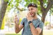 Young handsome sport man with a bottle of water at outdoors with surprise and shocked facial expression