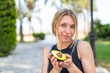 © luismolinero - Young blonde woman at outdoors holding an avocado