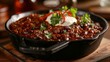 A cast iron skillet sizzling with a rich red chili con carn