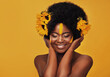 © peopleimages.com - Beautiful woman, sunflowers in hair and make up on face in studio for cosmetics, afro care and empowerment. Happy, black lady and yellow paint on forehead for summer, spring or warmer weather