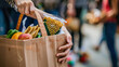 © sommersby - A person standing outdoors holding a shopping bag filled with various fresh fruits and vegetables