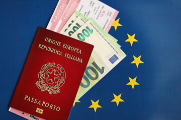 Wall Mural - Italian passport of European Union and airlines tickets on blue flag background close up. Tourism and travel concept