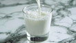 The fresh milk contained in a carafe is poured into a glass ,Pouring a healthy glass of fresh milk against a white background ,Glass of Milk lover ,Milk is poured make wave