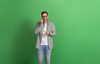 Portrait of handsome freelancer holding credit card and talking over smart phone on green background