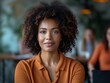 © MaxK - A woman with curly hair is smiling at the camera. She is wearing a brown shirt and gold earrings