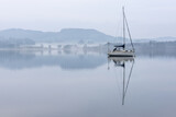 Fototapeta Londyn - Stunning peaceful landscape image of misty Spring morning over Windermere in Lake District and distant misty peaks