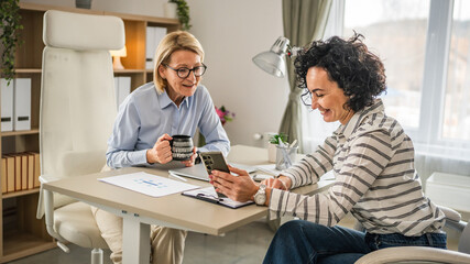 Wall Mural - Two mature woman have coffee break at office