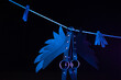bdsm leather shoulder straps in the shape of wings hanging on a clothesline in neon light on a black background, conceptual photos