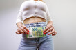 © Roman - The girl is holding hundred euro bills in the front of her jeans. A girl in jeans with a euro banknote in her hands.