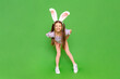 A teenage girl with rabbit ears. A little girl dressed up as an Easter bunny is enjoying a happy Easter holiday. Green isolated background. A full-length child. Copy space.