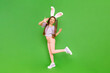 A teenage girl with rabbit ears. A little girl dressed up as an Easter bunny is enjoying a happy Easter holiday. Green isolated background. A full-length child. Copy space.