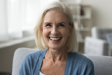 Head shot portrait merry mature woman laughing looking at camera, take part in videocall event with family, profile picture of videoconference virtual meeting participant. Happy mood, leisure at home