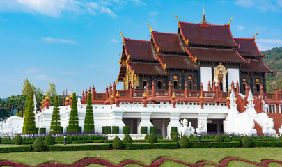 Wall Mural - A large building with a red roof and white trim. The building is surrounded by a lush green lawn and has a white facade