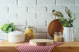 Fototapeta  - Empty wooden log  on kitchen table with food jars and plants over white brick wall  background.  Kitchen mock up for design and product display.