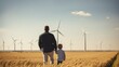 Back view of son on father's shoulder pointing ahead, field seeing wind turbines 