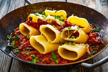 Sticker - Paccheri con ragù alla bolognese - noodles with bolognese sauce on frying pan on wooden table
