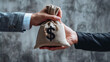 A businessman hands over an open money bag with a dollar sign to another person isolated on a grey background in a closeup view