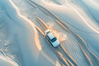 Aerial drone view of a car on desert sand dunes.