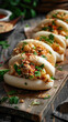 Delicious bao buns with chicken filling - Freshly prepared chicken bao buns garnished with green onions and spices, served on a rustic wooden board