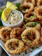 Golden Crispy Fried Calamari with Lemon and Sauce - Freshly prepared, golden brown fried calamari rings served with a side of lemon slices and creamy dipping sauce for a delicious appetizer