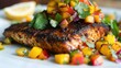 Grilled salmon with mango salsa on plate - Succulent grilled salmon topped with a vibrant mango salsa, garnished with fresh cilantro and a squeeze of lemon