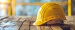 Yellow safety helmet on a wooden surface at a construction site. Industrial safety and protection concept