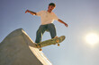 Bottom view of young man doing tricks on his skateboard at the skate park. Active sport concept