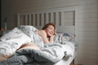 Young happy woman in bed. Morning, awakening. She smiles. Holidays and weekends.