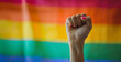 A woman protests with her fist raised on gay pride day with the LGBT flag in the background