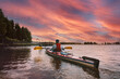 Father and son kayaking together in a lagoon at sunset. Concept: Adventure, Sport, Fun.