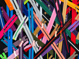 Poster - A colorful assortment of zippers are spread out on a black background. The zippers come in a variety of colors and sizes, creating a vibrant and lively scene. Concept of creativity and playfulness