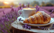 Cup of coffee with croissant on the background of a lavender field