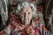 Elderly woman sitting in chair with floral blanket, suitable for healthcare or retirement concepts