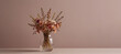 Transparent vase with a bouquet of dried flowers on a plain background