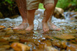 © IQRA - A cute father and baby's feet splashing in a shallow stream, with pebbles at the water's edge.