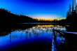 Blue hour over mountain lake with trees, grass, log