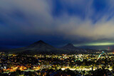 Fototapeta Kwiaty - Mountain and city lights at night, clouds, 