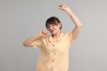 Wall Mural - Woman in pyjama stretching on grey background