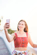 Bright portrait of a young woman taking selfie outdoors at sunset