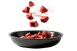 Pieces of meat flying in a frying pan on a transparent background