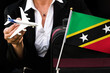 business woman holds toy plane travel bag and flag of Saint Kitts and Nevis
