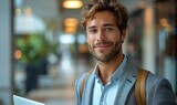 Fototapeta  - A personable man with light curls and a gentle smile holds a laptop, situated in a stylish cafe environment