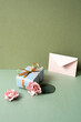 Blue gift box and envelope card with pink rose on green table. khaki wall background. birthday celebration concept