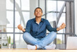 Calm African American young man sitting on the workplace in the office and meditation taking break avoiding stressful job