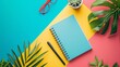 Creative flat lay of tropical leaves, notepads and sunglasses on vibrant tricolor background