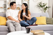 Happy Asian Couple Relaxing Together At Home, Engaging In Intimate Conversation On A Comfortable Couch, Showing Affection And Joy, Modern Living Room Setting