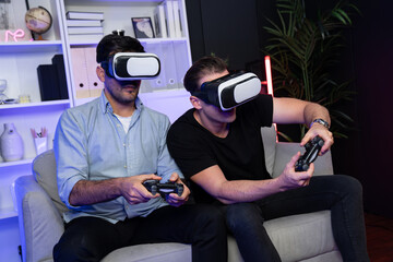 Wall Mural - Buddy friend gamers playing video game using joysticks and VR headset of virtual technology in reality in studio room with neon blue light. Comfy living indoor with cheerful fighting winner. Sellable.