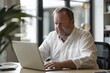 © ChaoticMind - An attentive middle-aged businessman works diligently on a laptop at his office desk