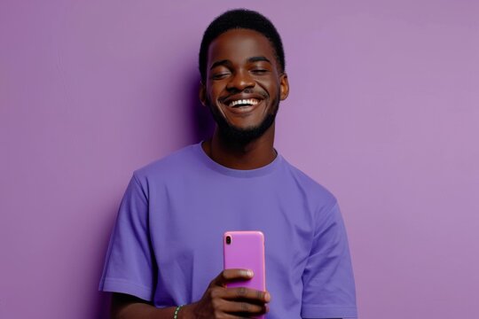 Portrait of a cheerful man with a bright smile looking at his smartphone on a vibrant purple backdrop