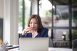 Asian businesswomen reading marketing business report and finance chart on laptop to thinking about strategy of new business while analyze investment and market stock of new startup in outside office
